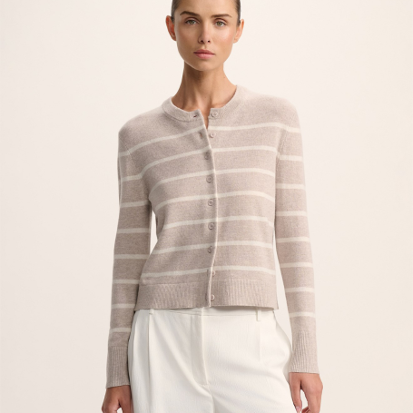 Woman wearing a striped knit button up (coloured a pale dusty pink and white) with white pleated pants.