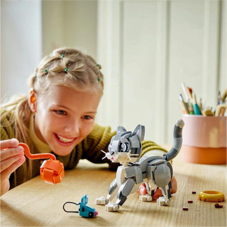 A girl playing with a LEGO cat and LEGO mouse.