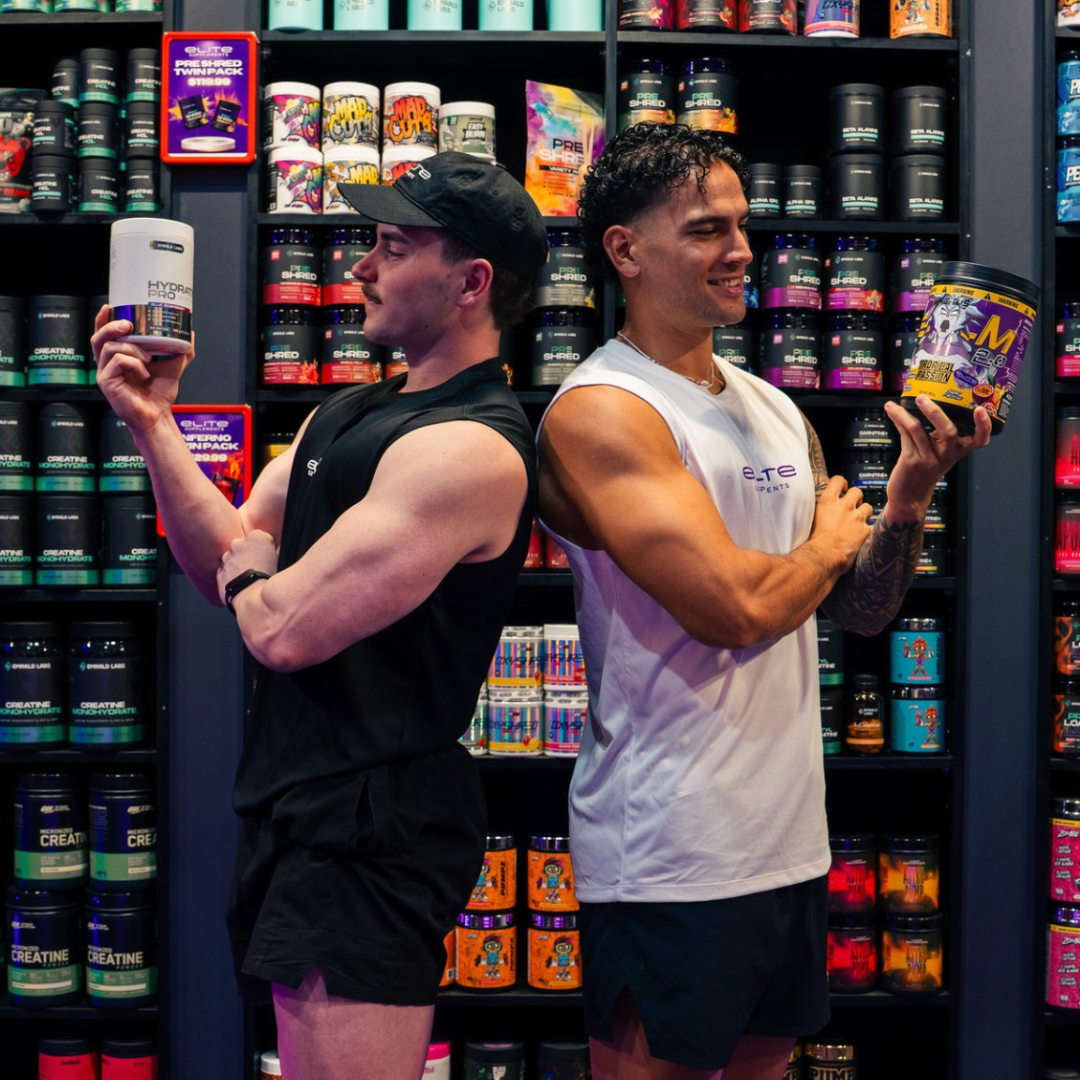 Two men standing back to back holding items from Elite Supplements